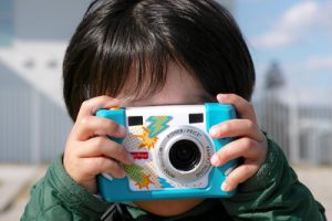 A little child holding a camera to their face